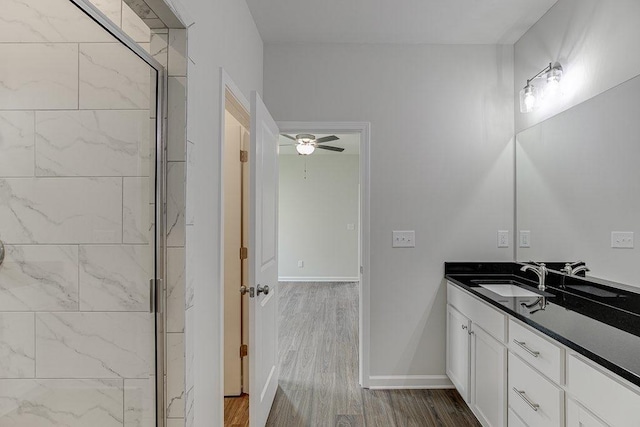 full bathroom with ceiling fan, wood finished floors, vanity, baseboards, and a shower stall