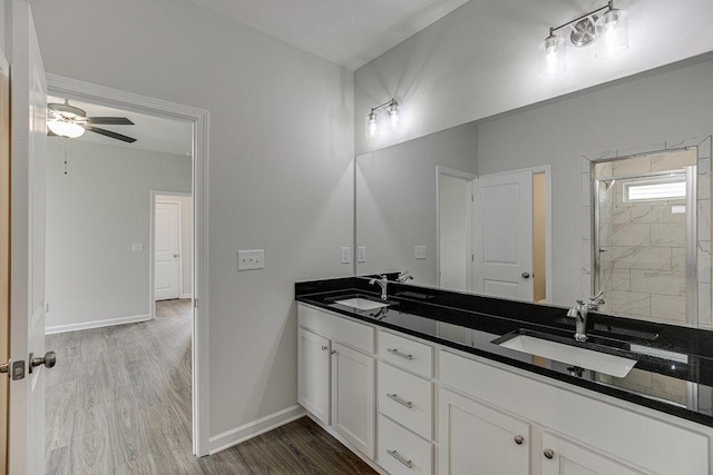 full bath with double vanity, baseboards, a sink, and wood finished floors