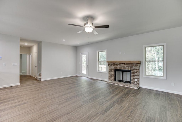 unfurnished living room with baseboards, ceiling fan, wood finished floors, a fireplace, and recessed lighting