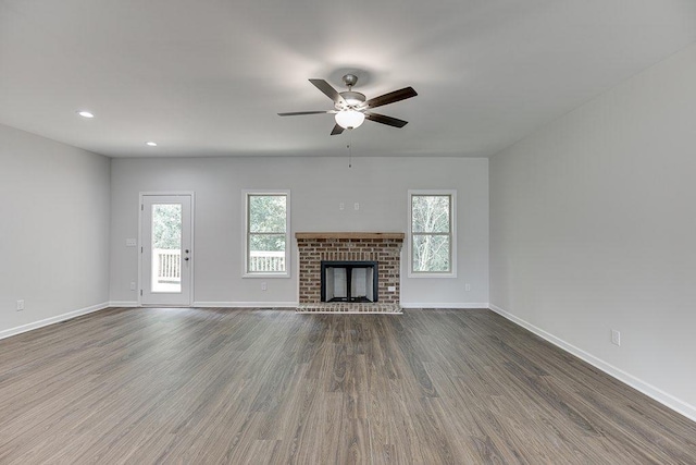 unfurnished living room with a fireplace, dark wood finished floors, a ceiling fan, and baseboards