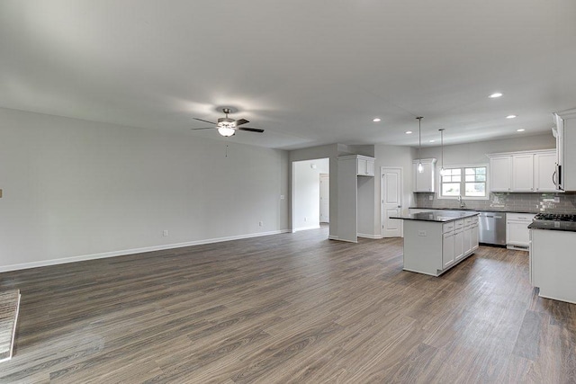 kitchen with dark wood-type flooring, a kitchen island, open floor plan, appliances with stainless steel finishes, and dark countertops