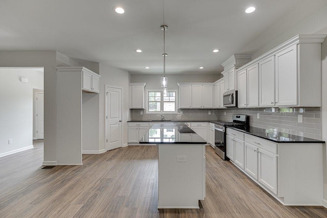 kitchen with appliances with stainless steel finishes, dark countertops, light wood-type flooring, and a sink