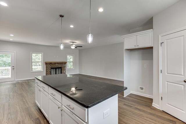 kitchen featuring dark wood-style floors, pendant lighting, a fireplace, dark countertops, and white cabinets