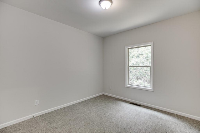 carpeted spare room featuring visible vents and baseboards