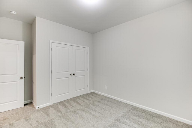 unfurnished bedroom featuring carpet, baseboards, and a closet