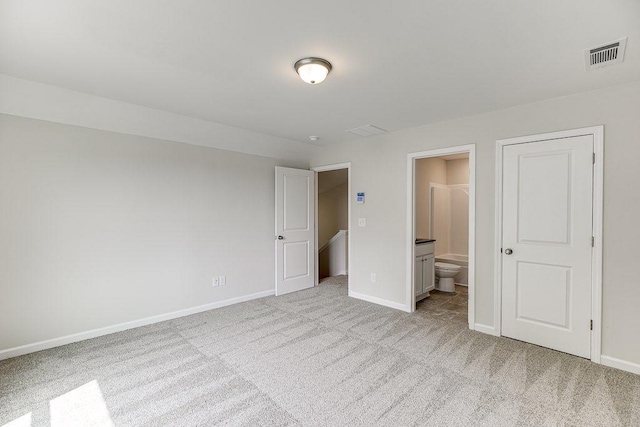 unfurnished bedroom with baseboards, connected bathroom, visible vents, and light colored carpet