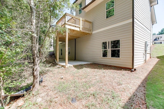 rear view of house featuring a wooden deck and a patio