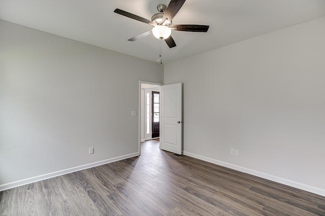 spare room featuring dark wood finished floors, a ceiling fan, and baseboards