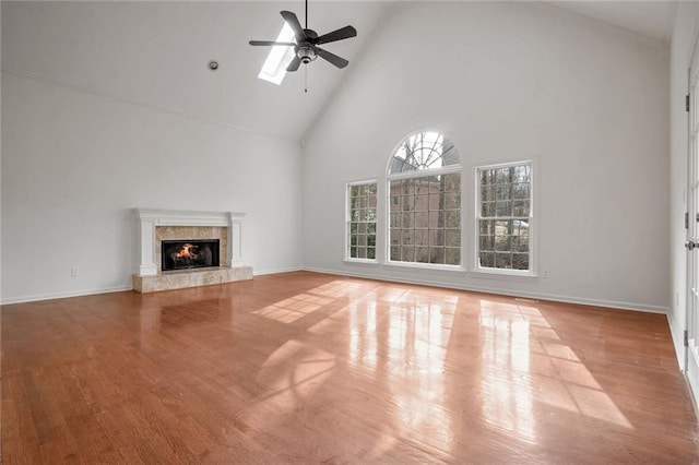 unfurnished living room with ceiling fan, a high end fireplace, high vaulted ceiling, and light hardwood / wood-style flooring