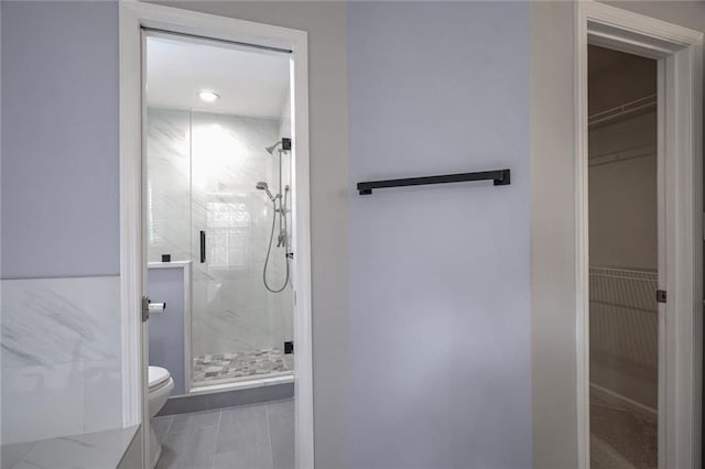 bathroom featuring toilet, tile patterned flooring, and a shower with door