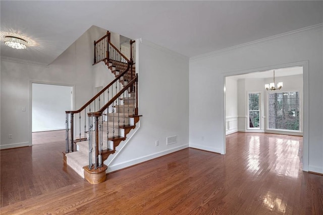 unfurnished living room featuring an inviting chandelier, ornamental molding, and dark hardwood / wood-style floors