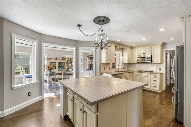 kitchen featuring pendant lighting, sink, appliances with stainless steel finishes, cream cabinets, and a wealth of natural light