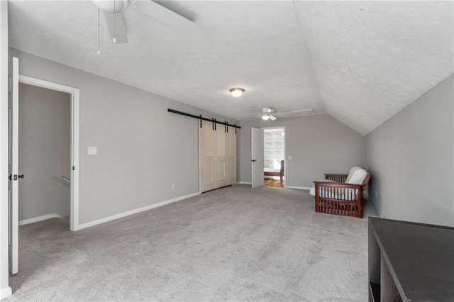 interior space with light carpet, a barn door, and a textured ceiling