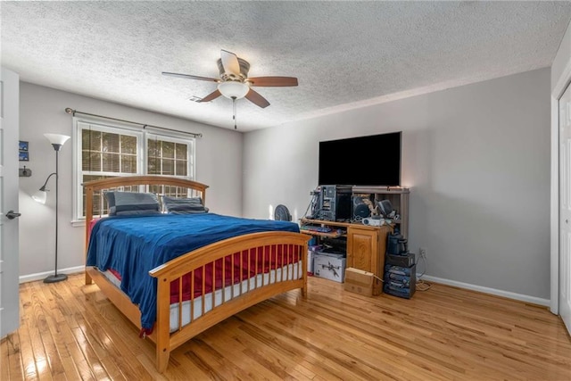 bedroom with ceiling fan, a textured ceiling, and light hardwood / wood-style floors