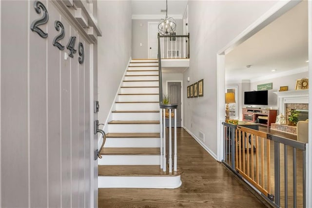 stairs with ornamental molding, hardwood / wood-style floors, and a chandelier