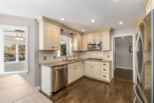 kitchen featuring sink, stainless steel appliances, dark hardwood / wood-style floors, decorative light fixtures, and cream cabinetry