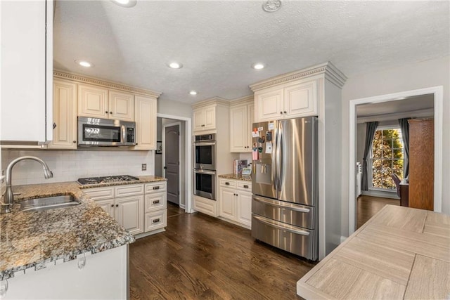 kitchen with stone counters, appliances with stainless steel finishes, sink, decorative backsplash, and dark wood-type flooring