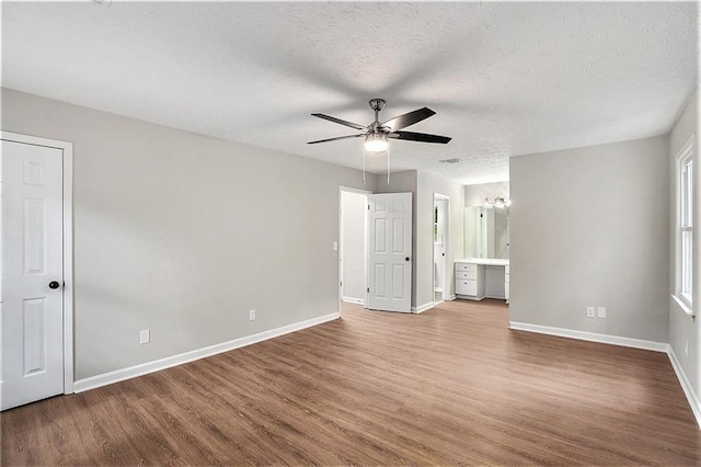 unfurnished room with a textured ceiling, wood finished floors, a ceiling fan, and baseboards