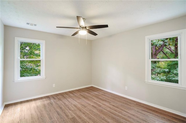 spare room with baseboards, visible vents, ceiling fan, and wood finished floors