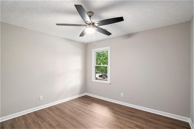 empty room featuring dark wood-type flooring, ceiling fan, a textured ceiling, and baseboards