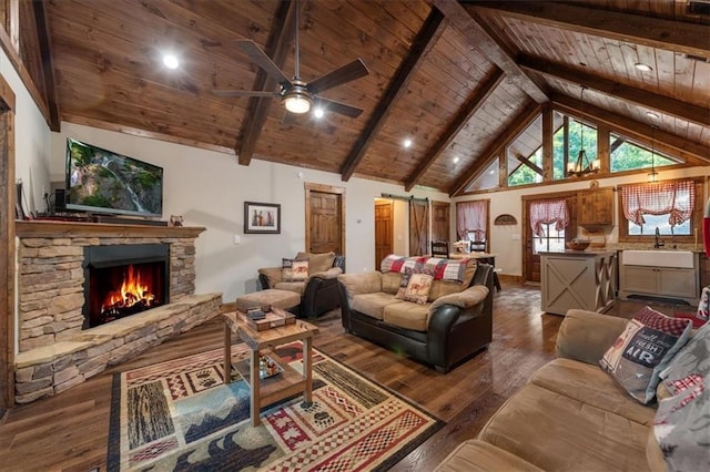 living room featuring dark hardwood / wood-style flooring, a stone fireplace, wooden ceiling, beam ceiling, and a barn door