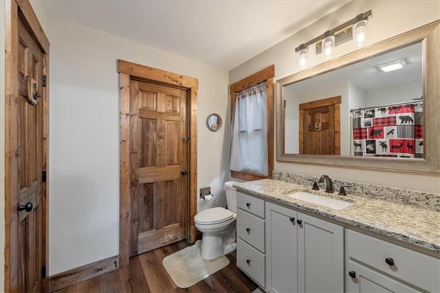 bathroom with hardwood / wood-style floors, toilet, and vanity