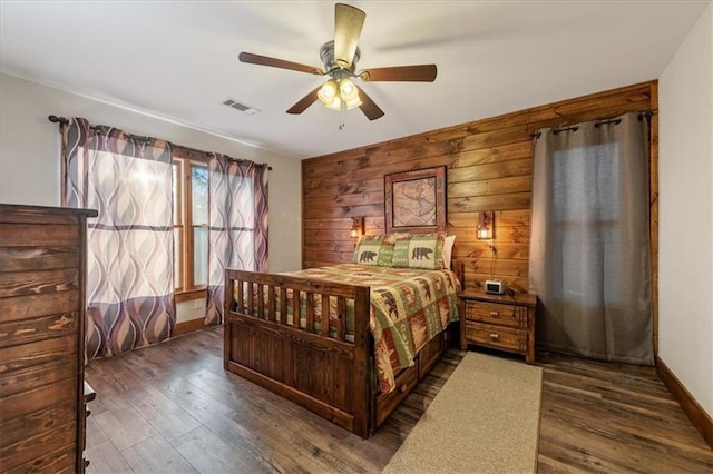 bedroom with ceiling fan, wood walls, and dark hardwood / wood-style floors