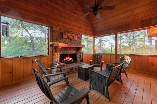 sunroom / solarium with vaulted ceiling, ceiling fan, an outdoor stone fireplace, and wooden ceiling