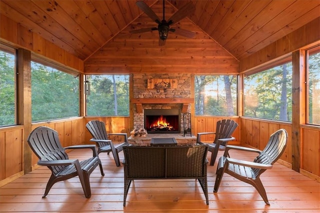 sunroom / solarium featuring ceiling fan, vaulted ceiling, an outdoor stone fireplace, and wood ceiling