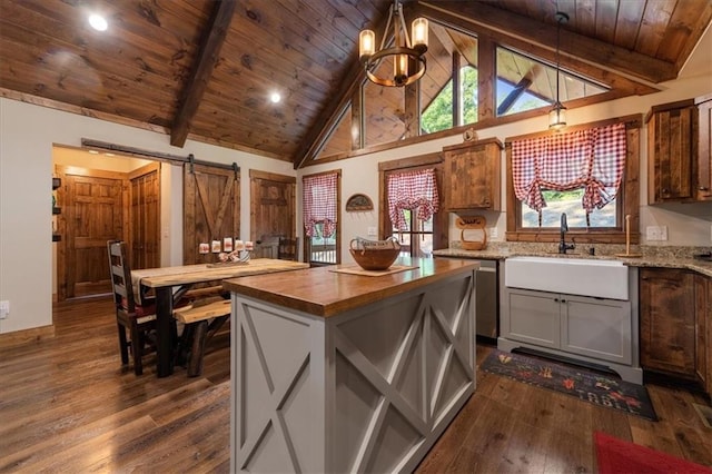 kitchen with pendant lighting, beam ceiling, a center island, and a barn door