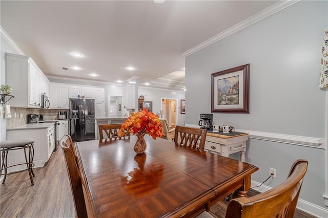 dining area with light hardwood / wood-style flooring and ornamental molding