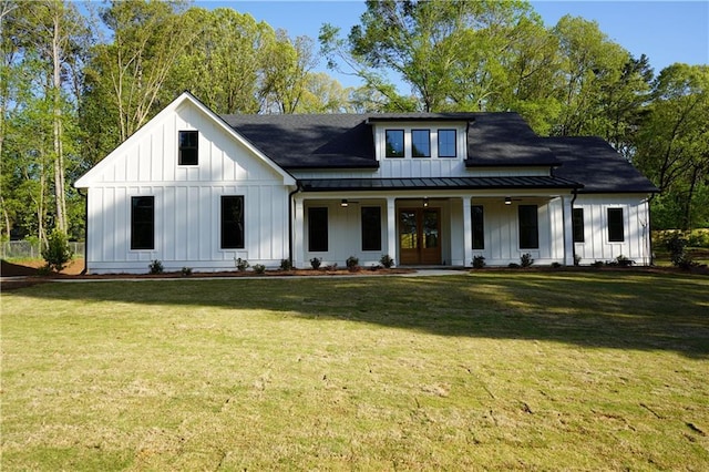 modern farmhouse featuring board and batten siding, a front yard, metal roof, and a standing seam roof