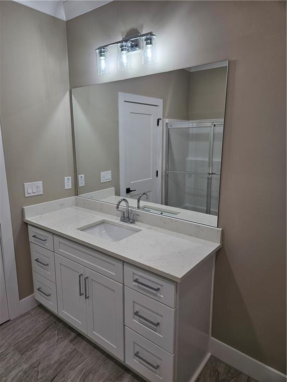 bathroom featuring an enclosed shower, baseboards, vanity, and wood finished floors