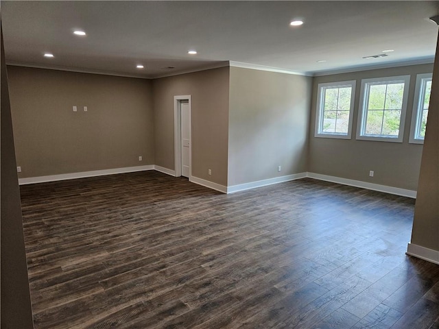 spare room with dark wood-style flooring, baseboards, ornamental molding, and visible vents
