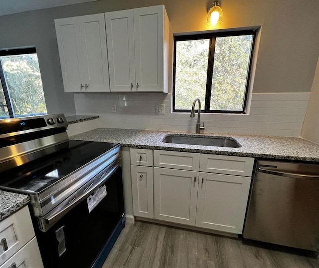 kitchen with tasteful backsplash, light hardwood / wood-style flooring, sink, appliances with stainless steel finishes, and white cabinets