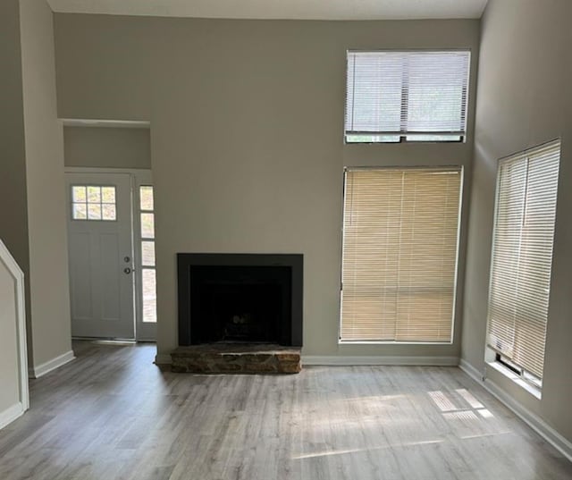 3932 Darryl Ln, Gainesville, GA 30506 - unfurnished living room with a wealth of natural light, wood finished floors, a towering ceiling, and a fireplace with raised hearth