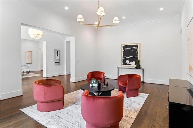 living area with dark hardwood / wood-style floors, crown molding, and a notable chandelier