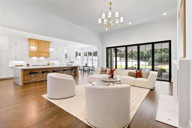 living room featuring dark hardwood / wood-style flooring, an inviting chandelier, and ornamental molding