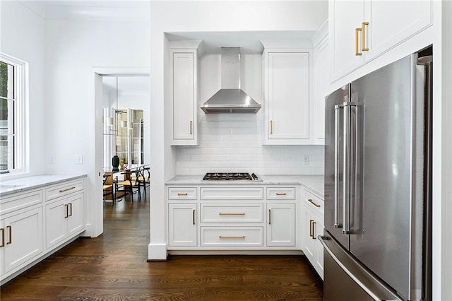 kitchen featuring stainless steel appliances, dark hardwood / wood-style flooring, white cabinets, wall chimney range hood, and backsplash