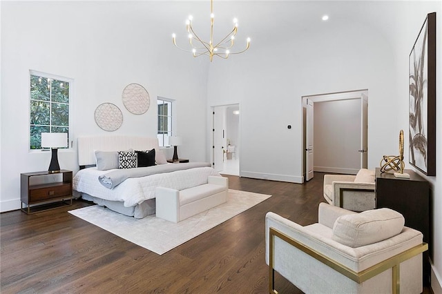 bedroom with dark wood-type flooring, a chandelier, and a towering ceiling