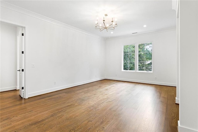 empty room featuring a notable chandelier, hardwood / wood-style flooring, and crown molding