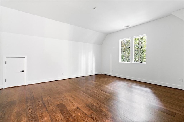 additional living space with hardwood / wood-style floors and vaulted ceiling