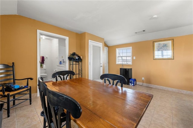 dining space featuring light tile patterned floors and vaulted ceiling