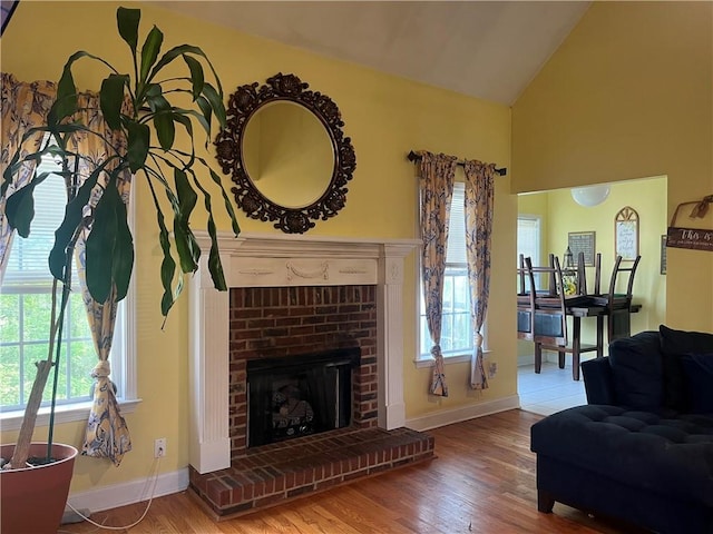 living room featuring baseboards, high vaulted ceiling, and wood finished floors