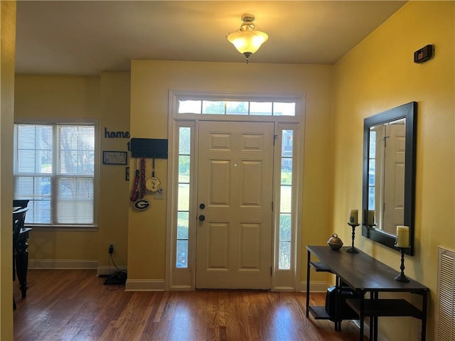 foyer featuring baseboards, wood finished floors, and visible vents
