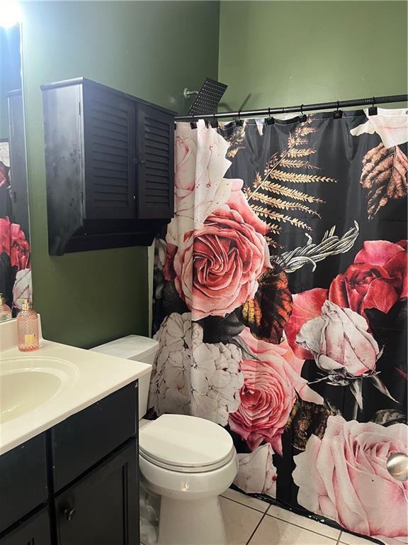 bathroom featuring vanity, tile patterned flooring, toilet, and curtained shower