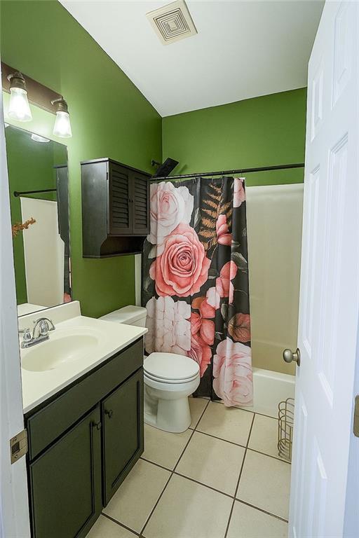 full bath with visible vents, tile patterned floors, vanity, toilet, and shower / bath combo with shower curtain