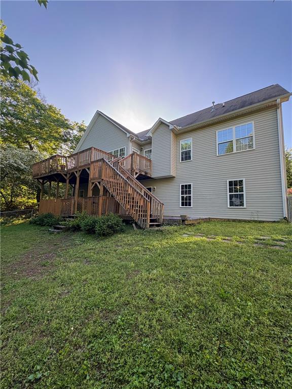 rear view of property featuring a wooden deck, a yard, and stairway