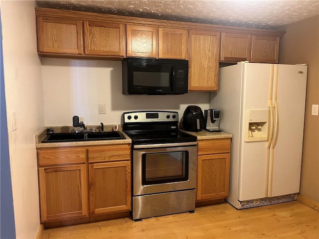 kitchen featuring black microwave, a sink, white refrigerator with ice dispenser, electric stove, and light wood-type flooring