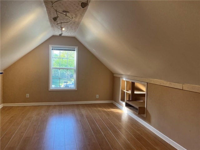 bonus room with baseboards, vaulted ceiling, and hardwood / wood-style flooring